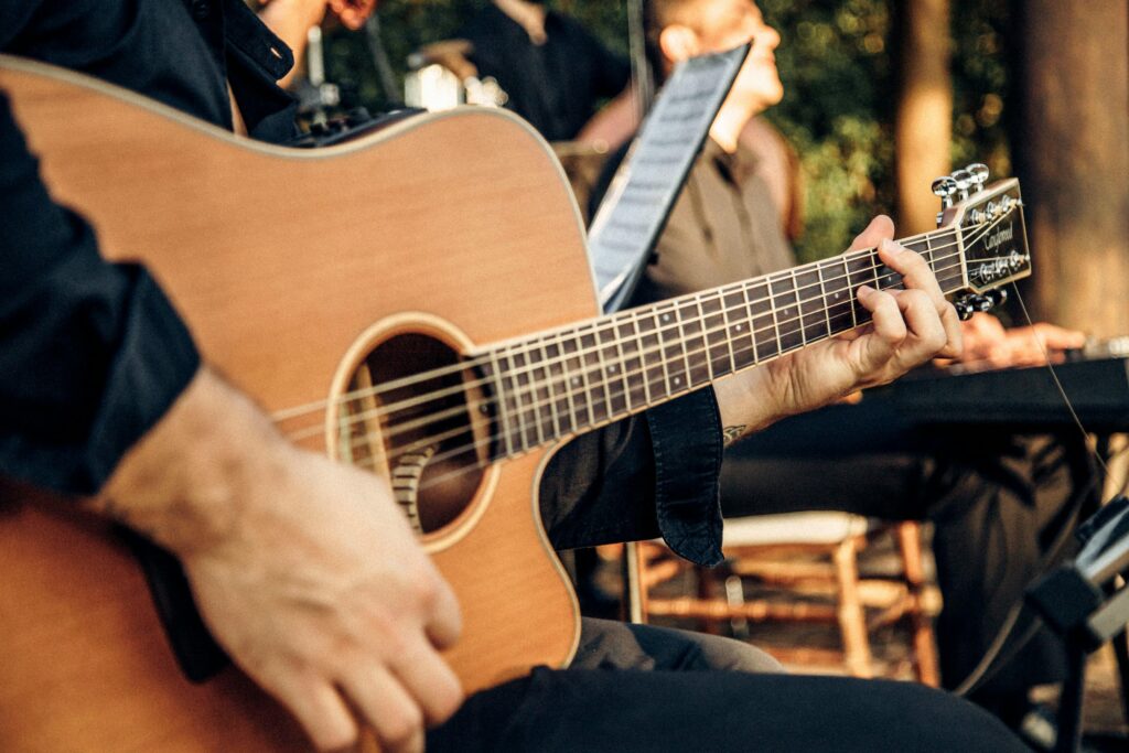 Close-up of a man playing an acoustic guitar at an outdoor concert, capturing the essence of live music.