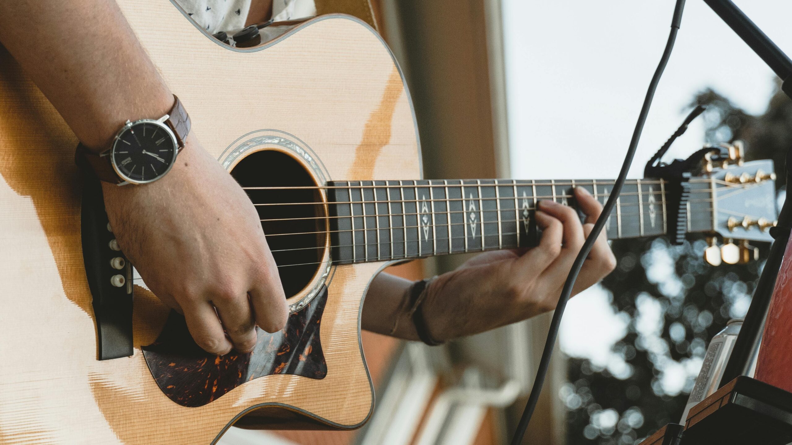 A musician's hands skillfully playing an acoustic guitar, showcasing musical artistry.