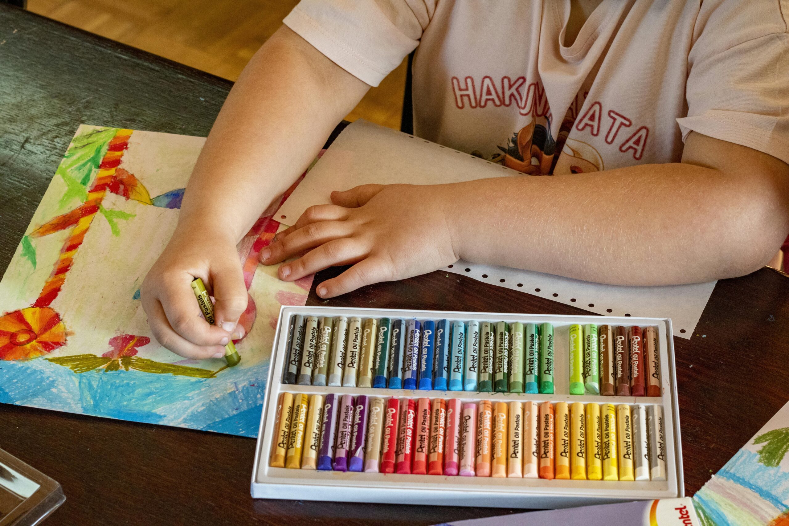 A child drawing vibrant artwork using oil pastels on paper, focusing on creativity and art.